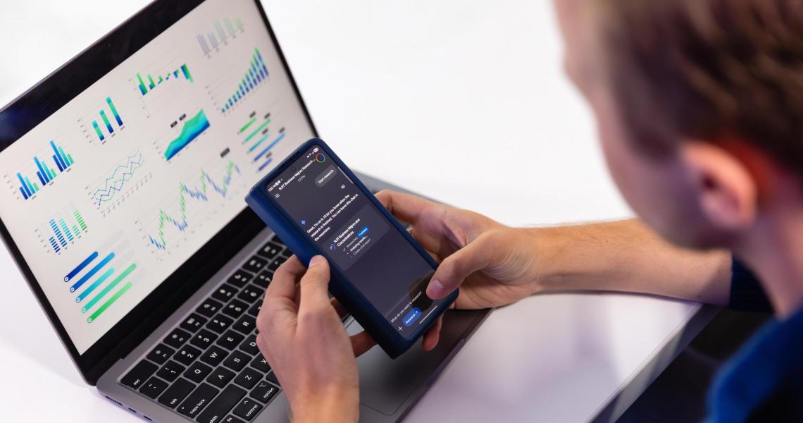 Person viewing charts on laptop and phone.