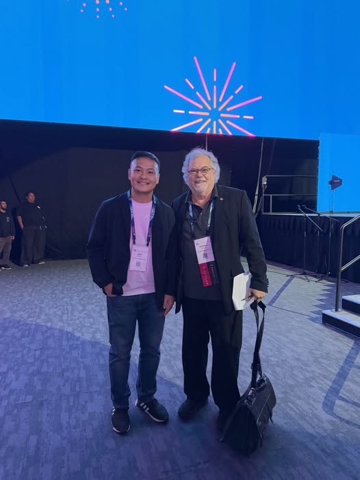 Two men smiling at an event stage.