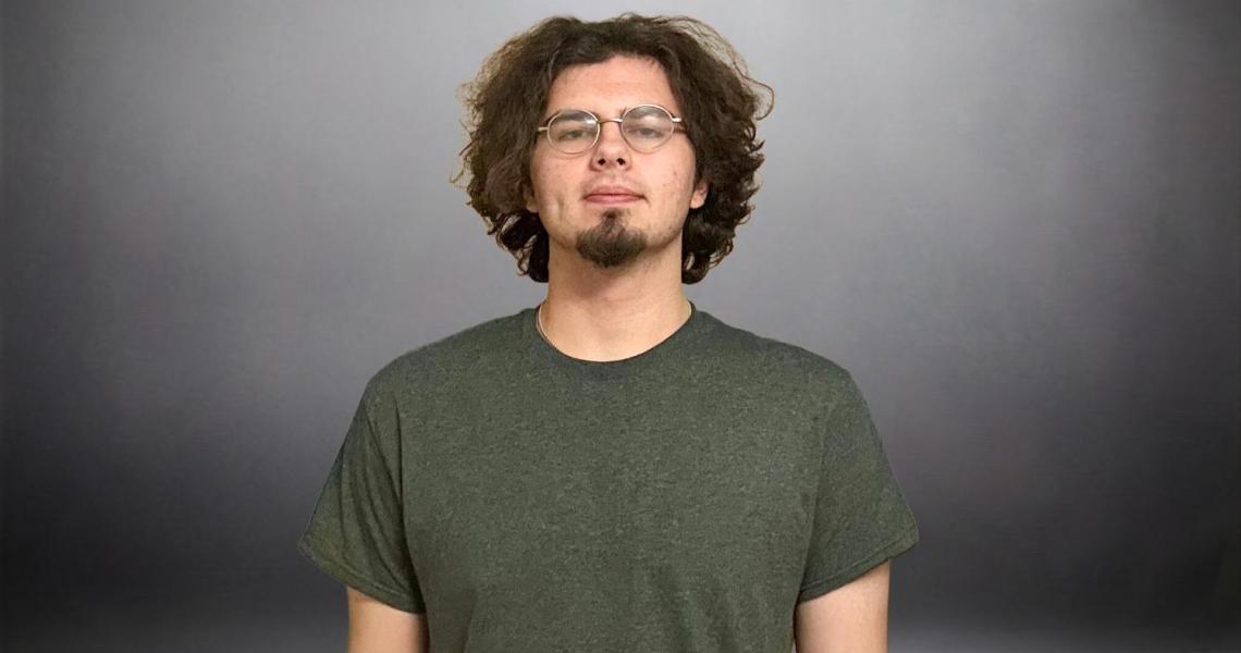 Man with glasses and curly hair in grey shirt.