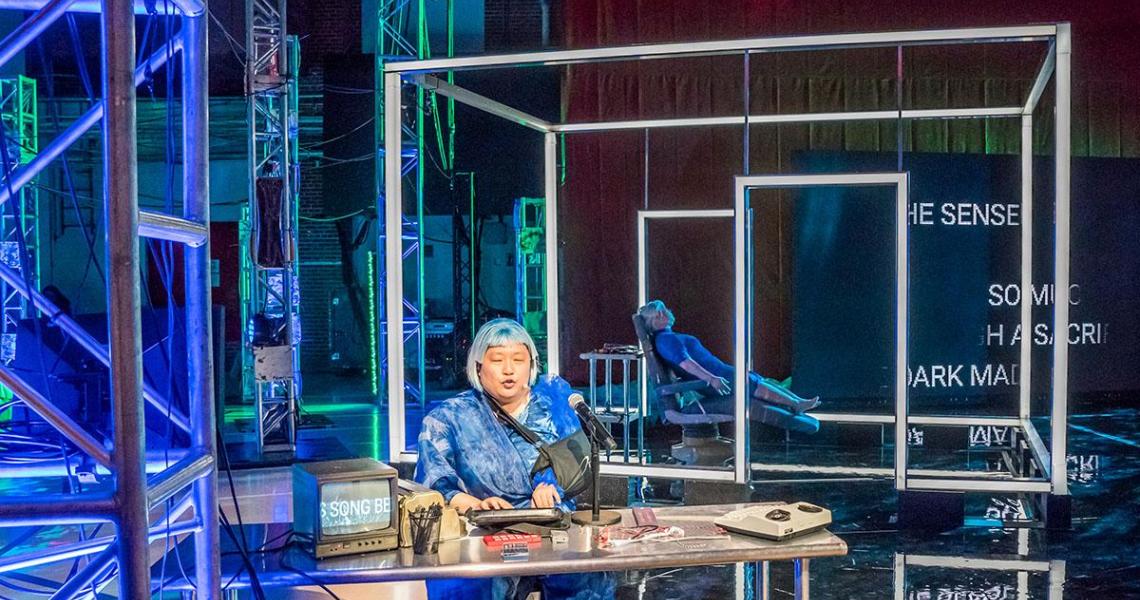 Person performing on stage with blue lighting.