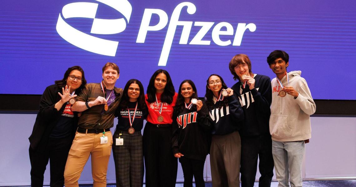 Group of students with medals at Pfizer event.
